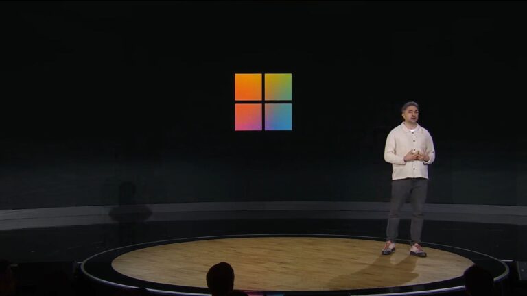 Mustafa at Microsoft 50th Anniversary event in front of Windows logo