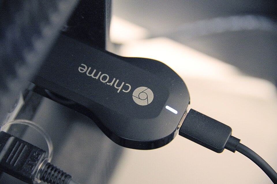 A Chromecast streaming device plugged into the HDMI port of a television