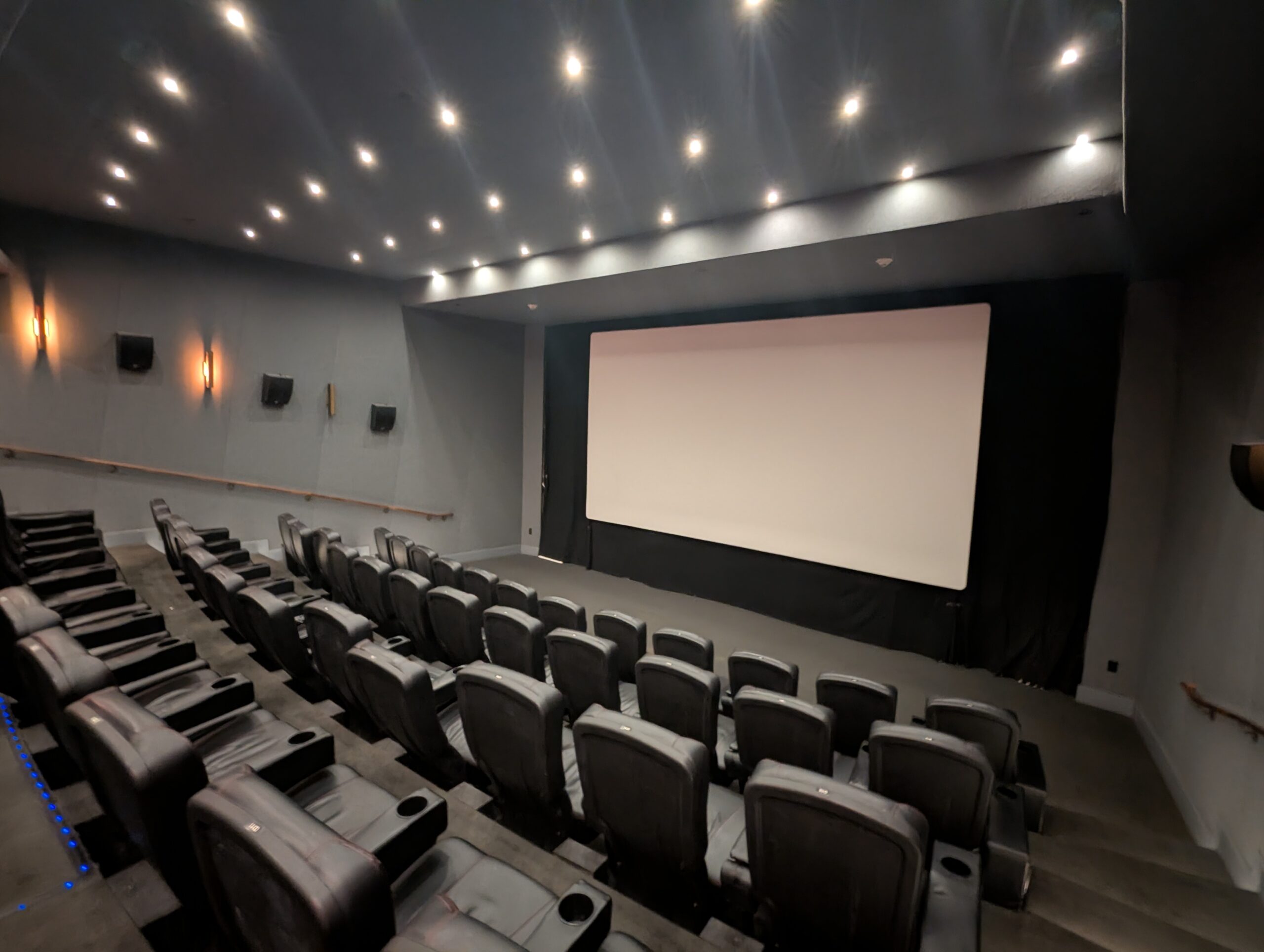 An empty cinema screening room with rows of seats facing the screen