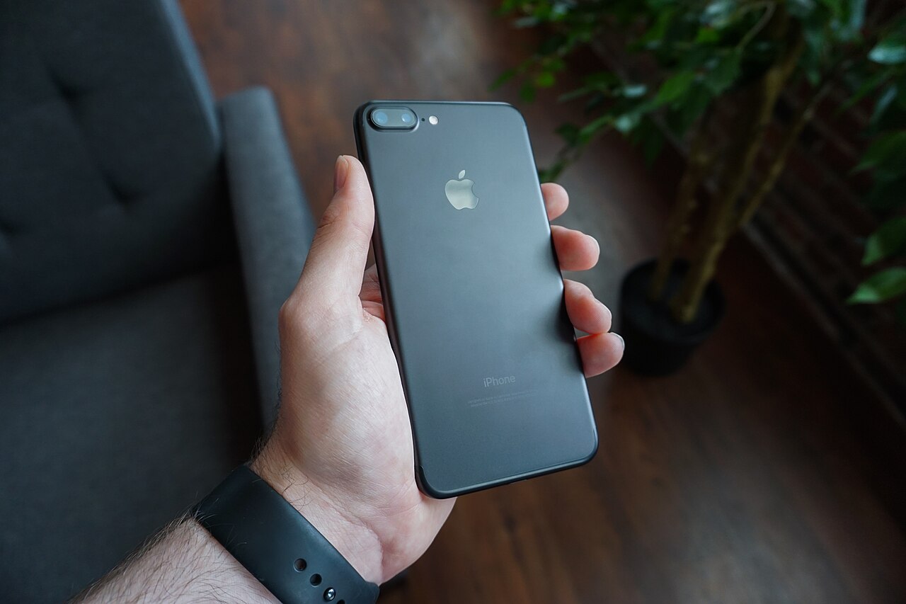 A person holding a black smartphone, the kind of device foldable phones are designed to replace